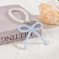 Gros plan d'un pendentif nœud en perles bleues avec perles blanches sur fond rose - Style Chaîne de Perles Bleue