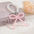 Détail macro d'un pendentif nœud en perles roses avec fermoir argenté sur un livre - Style Chaîne de Perles Rose