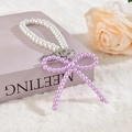 Détail d'un porte-clés perlé avec nœud violet et perles blanches sur un livre - Style Chaîne de Perles Violette