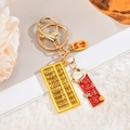 Detailansicht eines goldenen Abakus-Schlüsselanhängers mit Maneki-neko und Glücksbringer - Wohlstand und Reichtum
