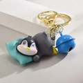 Portachiavi con simpatico pinguino e campanellino blu su sfondo grigio chiaro minimal - Pinguino con Cuscino / Fibbia Dorata + Pinguino + Campanello