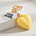 Close-up of golden heart keychain with transparent acrylic pendant and yellow heart - Yellow