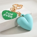 Detail of heart-shaped keychain with green acrylic tag and blue 3D silicone heart charm - Green