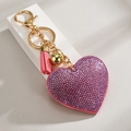 Close-up of heart keychain with purple rhinestones, pink tassel and golden bell - Pink
