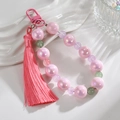 Detailed macro view of pink pearlescent beaded keychain with soft silk tassel and metal clasp - Pink