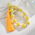 Dettaglio del portachiavi con perle gialle, nappa arancione e chiusura a moschettone - Giallo Limone