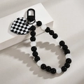 Detail van geblokte hartbedel aan zwart-witte kralenketting met metalen veerringsluiting - Gesp Ketting + Rasterstuk / Hart Oog Glimlach