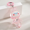 Pendentif lapin rose iridescent avec finition nacrée sur un présentoir géométrique - Porte-clés + Lapin Dansant / Anneau de couleur rose