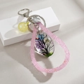 Detailed view of handmade teardrop resin pendant with life tree and dried flowers - Purple & Yellow