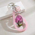 Macro detail of handmade resin pendant with pink cherry tree and butterfly crystal keychain - Pink