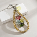 Detailed close-up of a handmade tree of life glass pendant with real dried flowers - Gold