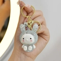Luminous blue crystal bunny keychain with gold metal ring held by hand in soft light - Blue