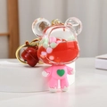 Pink bear liquid keychain with red fluid and colorful beads on a white pedestal - Red Bear