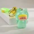 Cute glowing cartoon frog baby keychain with green strap and gold bell on a white stand - Green