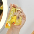 Detailed close-up of a glowing yellow duck liquid oil keychain with Be Playful wrist strap - Lemon Yellow Toilet