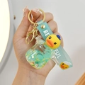 Macro shot of a mint green cartoon duck keychain with a glitter PVC strap and gold clasp - Blue Pressure Cooker