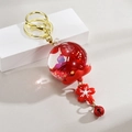 Détail d'un porte-clés cerisier japonais avec pétales séchés et fermoir mousqueton doré - Rouge