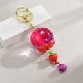 Dettaglio di un portachiavi a fragola con sfera in resina e fiori essiccati - Stile Fragola / Rosa Rosso