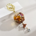 Détail du porte-clés boule en résine fleurs séchées avec champignon et cloche - Marron