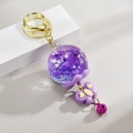 Dettaglio portachiavi con sfera in resina e fiori secchi viola e un piccolo campanellino - Design a Farfalla / Viola