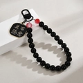 Close-up of black beaded charm with 'Everything Goes Well' gold-bordered metal plaque - Black Everything As Desired