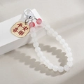 Detail of red bead pendant with gold tag engraved with Peace and Joy for bags - White Peace And Joy