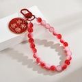 Macro detail of red beaded charm with golden Peace And Joy lettering on metal disk - Red Peace And Joy