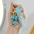 Detail of blue electroplated bear keychain with gold bell and translucent wrist strap - Blue