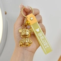 Close-up of golden electroplated bear keychain with translucent yellow wrist strap - Lemon Yellow