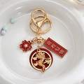Close-up of a festive Chinese dragon keychain with a lucky pendant and red floral charm - Splendid Future