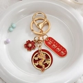 Détail d'un porte-clés dragon doré avec des breloques rouges Good Luck sur fourrure - Bonne Chance Continue