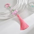 Pendentif gland rose avec perles vertes et breloques florales sur une assiette blanche - Anneau Coloré + Chaîne + Gland / Rose