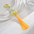 Détail de perles nuages jaunes et pendentif à pompon sur une assiette en céramique - Anneau Coloré + Chaîne + Gland / Jaune Citron