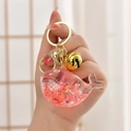 Detailed close-up of a cute pink whale liquid sand whale keychain with gold hardware - Luminous Red