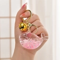 Handheld liquid quicksand whale keychain with pink glitter and gold bell accessory - Luminous Pink