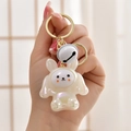 Pearlescent bunny keychain with golden ring and white bell charm held in hand - White Rabbit