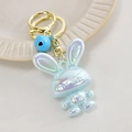 Macro shot of iridescent blue acrylic bunny keychain with LOVE relief and golden heart bell - Light Gold Buckle + Rabbit + Bell / Sky Blue