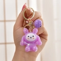 Close-up of cute purple iridescent rabbit keychain with small bell and golden hardware - Purple Rabbit