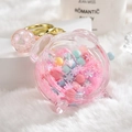 Pink acrylic astronaut keychain with liquid sand and golden ring on a soft white base - Alarm Clock Beads Pink