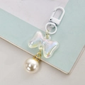 Detail of translucent iridescent bow pendant with white faux pearl and lobster clasp - White With Bell
