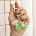 Detail of star-shaped liquid keychain with green sequins, palm tree and real seashells - Marine Series (Green) / Green