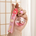 Detailed close-up of pink liquid quicksand keychain with rabbit and strawberry charm - Planet