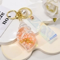 Macro view of shell keychain with iridescent PVC strap and pink inner pearls - Leather Strap + Small Conch + Pearl / Orange