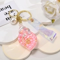 Shell-shaped keychain pendant with pink pearls, gold ring, and iridescent PVC strap - Leather Strap + Small Conch + Pearl / Pink