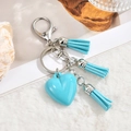 Detalle de un llavero de corazón azul claro con borlas suaves sobre felpa blanca - Cadena de Llavero + 3 Borlas / Corazón Azul Cielo
