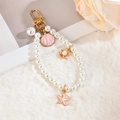 Charming ocean theme pearl keychain with shell and starfish charms on soft plush surface - Pink Ocean Style