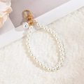 Elegant floral pearl keychain with golden clasp displayed on white faux fur background - White Large Pearl