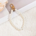 Detailed view of elegant pearl wrist strap with golden clasp on soft plush background - Simple Pearl Chain
