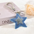 Dettaglio di un portachiavi a stella blu con strass scintillanti e nappine d'argento - Chiusura Argentata / Blu