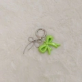 Close-up of a green resin bow and silver wire butterfly pendant on white fur - Fruit Green